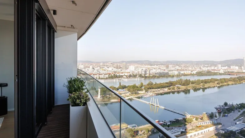 Geräumiger Balkon mit Glasbrüstung und weitem Blick über die Stadt und den Fluss.