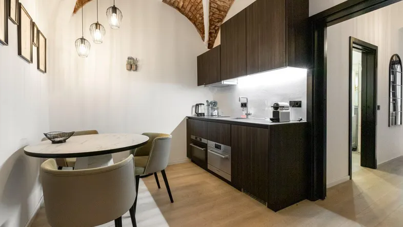 Moderne Küchenzeile mit dunklen Holzfronten, Esstisch und freigelegten Ziegelgewölben.