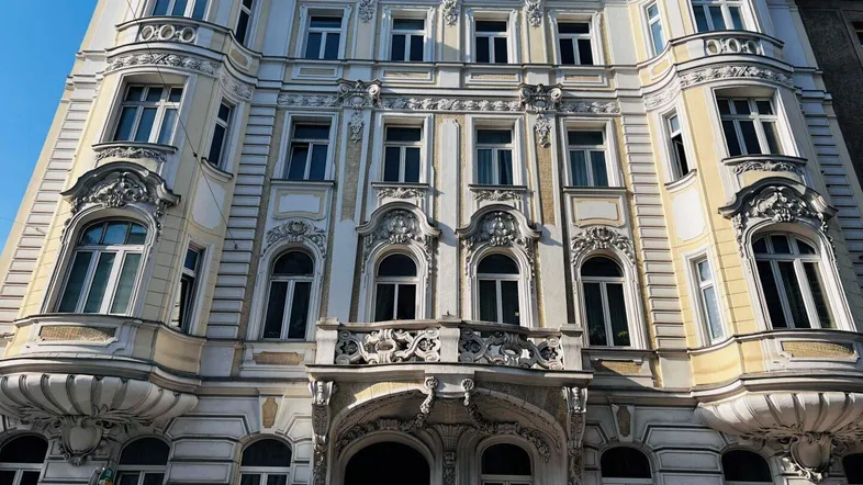 Prächtige historische Fassade eines Altbaus mit reich verzierten Details und vielen Fenstern.