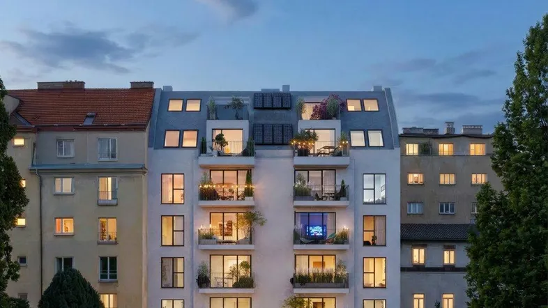Modernes Wohngebäude bei Dämmerung mit beleuchteten Balkonen, Solarpaneelen und begrüntem Dachgarten.