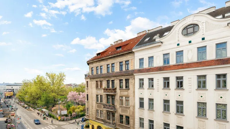 Blick auf die Straße mit historischen Gebäuden, Bäumen und blauem Himmel.
