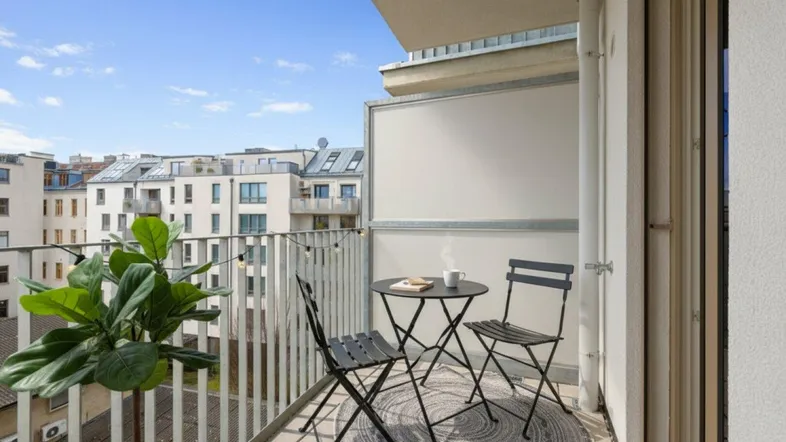 Möblierter Balkon mit Tisch und Stühlen, ideal für entspannte Stunden im Freien mit Blick auf die Stadt.