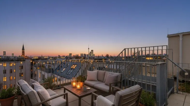 Gemütliche Dachterrasse mit bequemen Sitzmöbeln und weitem Blick über die Stadt bei Sonnenuntergang.
