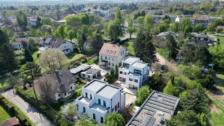 Luftaufnahme einer modernen Wohnsiedlung mit weißen Gebäuden, Flachdächern und viel Grün.