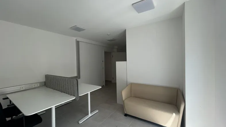 Geräumiger Bürobereich mit modernen Schreibtischen, Trennwänden und einem beigefarbenen Sofa.