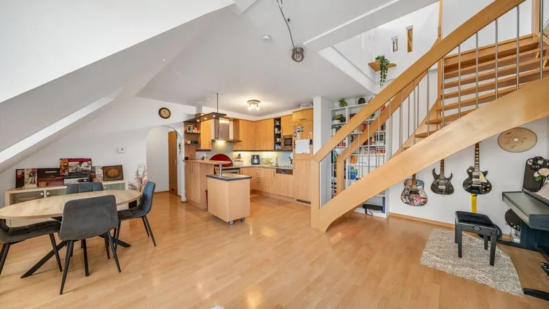 Geräumiger Wohn-Essbereich mit Holzboden, offener Küche und eleganter Holztreppe zum Obergeschoss.
