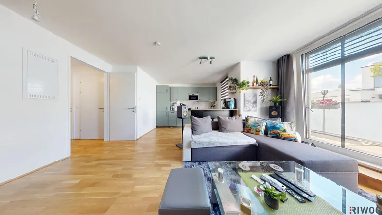 Geräumiger Wohnbereich mit Sofa, Holzboden und offener Küche im modernen Stil.