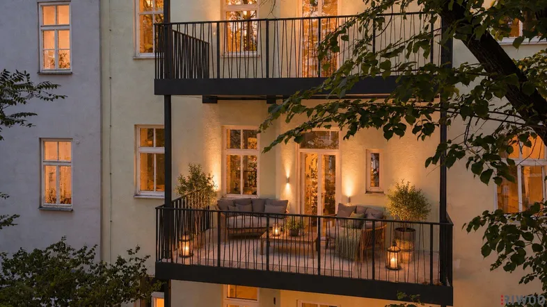 Beleuchteter Balkon am Abend mit gemütlichen Sitzmöbeln und Pflanzen.