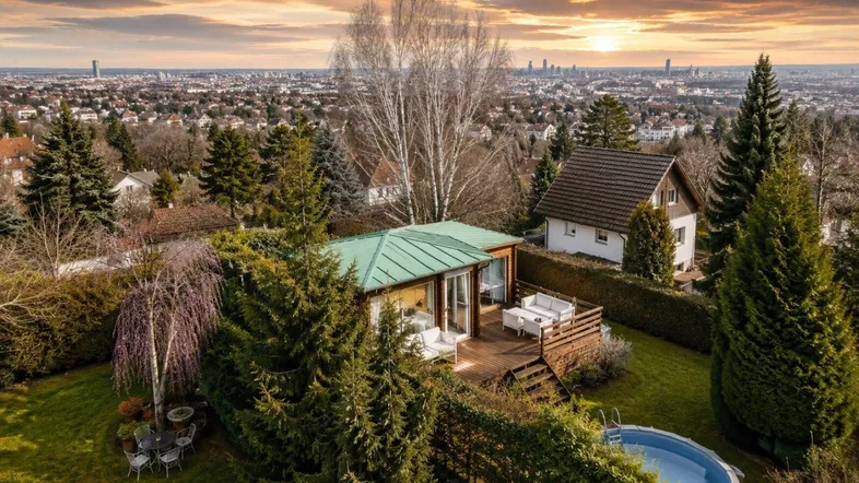 Panoramablick auf das Anwesen mit Garten, Pool und der Skyline der Stadt im Hintergrund.