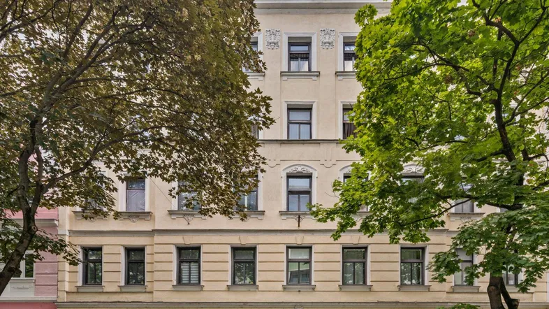 Klassische Fassade eines Mehrfamilienhauses mit vielen Fenstern und dekorativen Elementen.