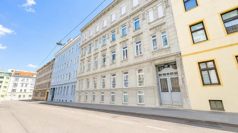Historisches Gebäude mit klassischer Fassade und großen Fenstern an einer städtischen Straße.
