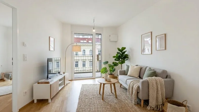 Helles Wohnzimmer mit Holzboden, modernem Sofa und Zugang zu einem kleinen Balkon.