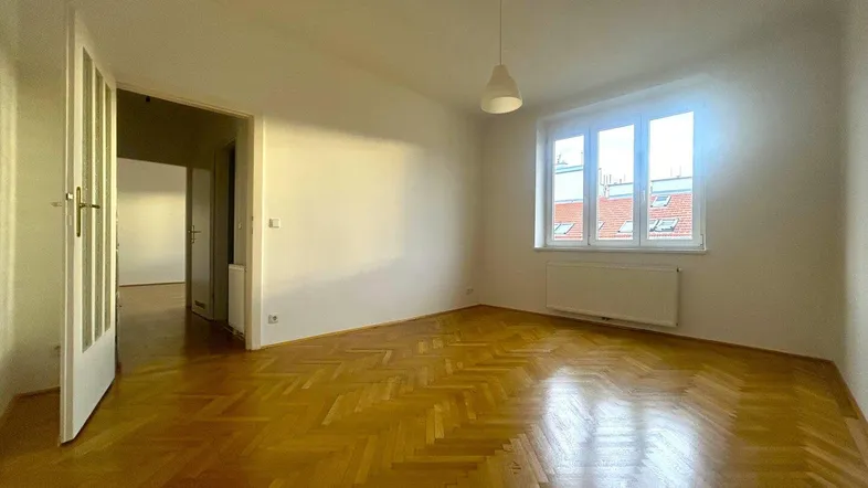 Helles Wohnzimmer mit Fischgrätparkettboden und Blick auf die Dächer der Stadt.