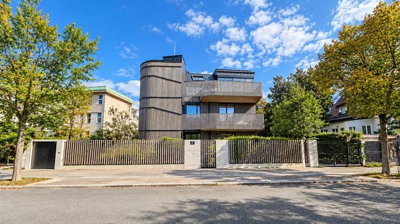 Moderne Wohnanlage mit markanter Holzfassade und gepflegter Außenanlage an einer ruhigen Straße.