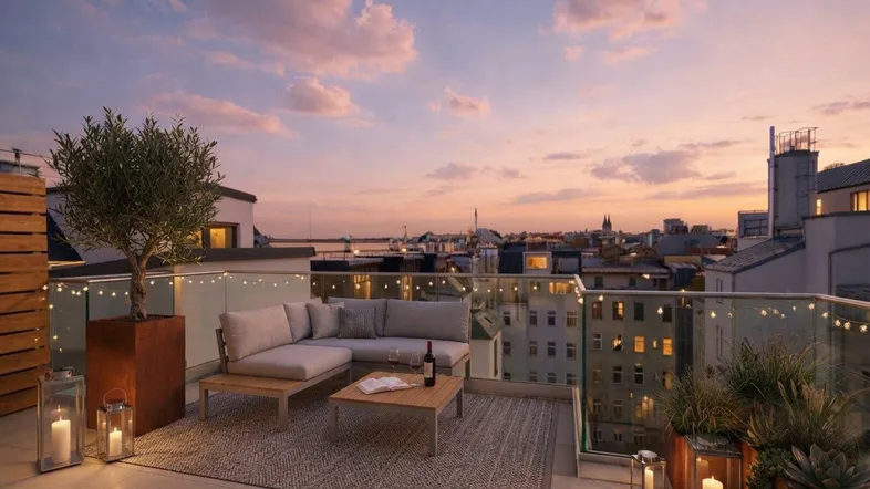 Geräumige Dachterrasse mit gemütlichen Sitzgelegenheiten, Pflanzen und stimmungsvoller Beleuchtung bei Sonnenuntergang.