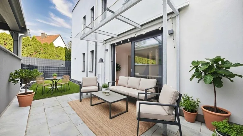 Moderne Terrasse mit bequemen Sitzgelegenheiten, Glasüberdachung und Zugang zu einem kleinen Gartenbereich.