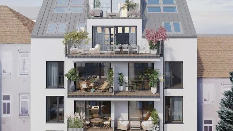 Moderne Wohnhaus-Fassade mit mehreren Balkonen und Dachterrassen unter klarem Himmel.