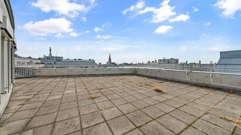Große gepflasterte Dachterrasse mit weitem Blick über die Stadt und den Himmel.