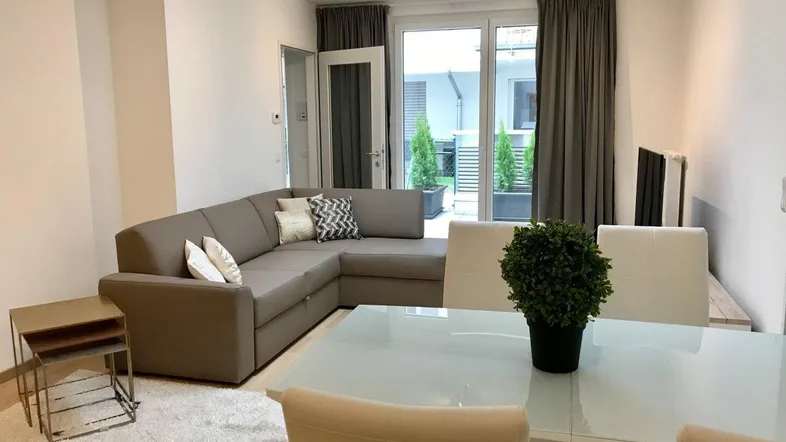 Helles Wohn- und Esszimmer mit Ecksofa, Esstisch und Zugang zur Terrasse.