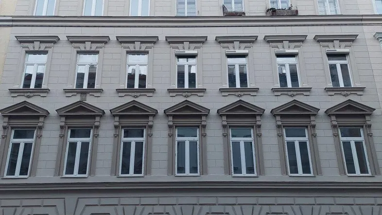 Klassische Fassade eines Altbaus mit vielen Fenstern und dekorativen Elementen in der Stadt.