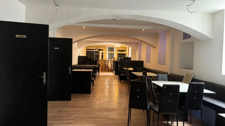 Geräumiger Innenbereich eines Gewerbeobjekts mit Tischen, Bänken und gewölbten Decken, ideal für Gastronomie.