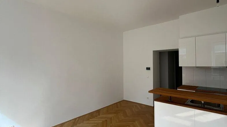 Heller offener Wohnbereich mit modernem Fischgrätparkett und integrierter Küchenzeile.