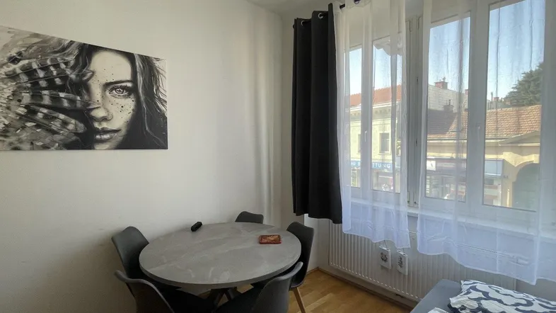 Helles Zimmer mit Esstisch, Schlafbereich und Blick auf die Straße.