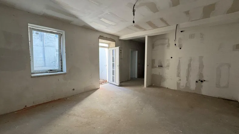 Geräumiger Rohbau-Raum mit Fenster und offenem Durchgang, bereit für den Innenausbau.