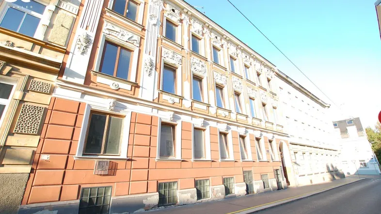 Historisches Gebäude mit aufwendiger Stuckfassade und großen Fenstern an einer ruhigen Straße.