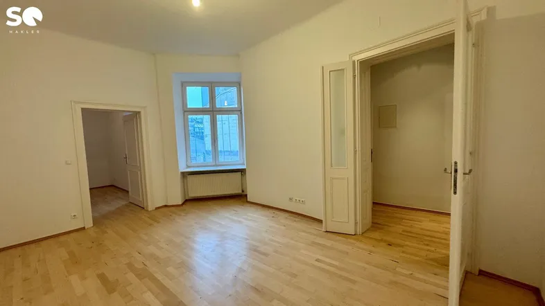 Geräumiges, unmöbliertes Zimmer mit hellem Parkettboden und hohen Decken, bereit zur individuellen Gestaltung.