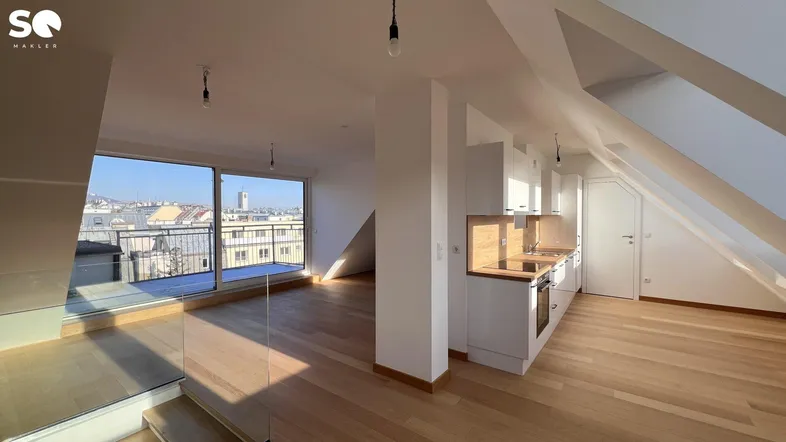 Heller offener Wohnbereich mit integrierter Küche, Holzboden und Zugang zu einem Balkon mit Stadtblick.