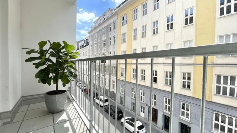 Geräumiger Balkon mit Blick auf die belebte Stadtstraße und umliegende Gebäude.