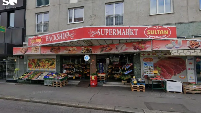 Fassade eines Supermarktes mit Backshop und darüber liegenden Wohnungen in einem städtischen Gebäude.