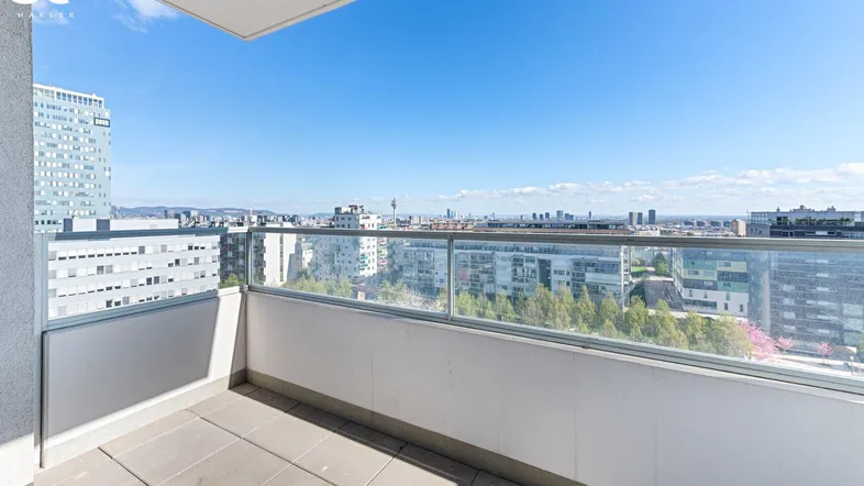 Geräumiger Balkon mit Glasbrüstung und weitem Blick über die Stadtlandschaft.