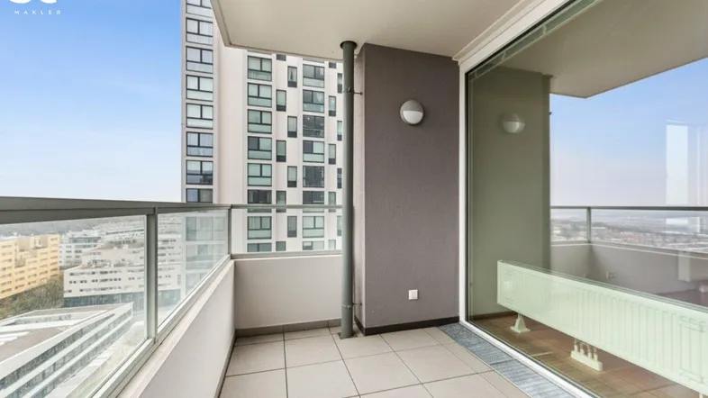 Moderner Balkon mit Fliesenboden und Glasgeländer, bietet einen weiten Blick über die Stadt.