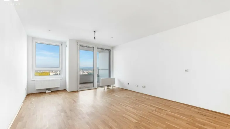 Helles Wohnzimmer mit Parkettboden, weißen Wänden und Zugang zu einem Balkon mit Stadtblick.