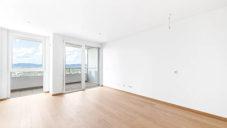 Helles Zimmer mit Parkettboden und Zugang zu zwei Balkonen mit Weitblick.