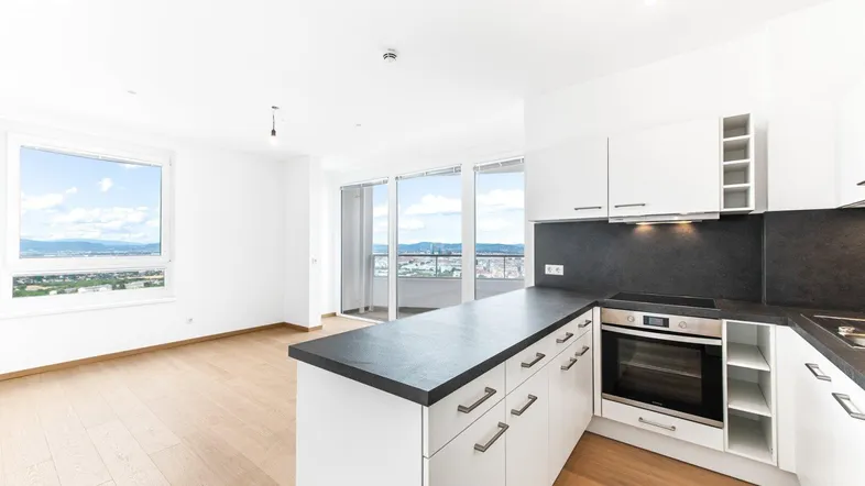 Helle offene Wohnküche mit moderner Ausstattung, Holzboden und weitem Stadtblick.
