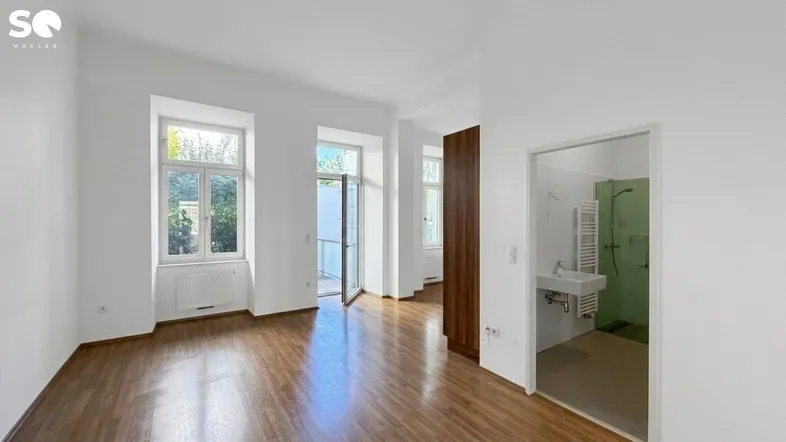 Heller Wohnraum mit Parkettboden, großen Fenstern und direktem Zugang zur Terrasse.