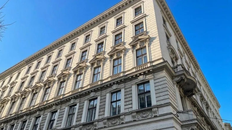 Historisches Gebäude mit reich verzierter Fassade, vielen Fenstern und architektonischen Details unter blauem Himmel.