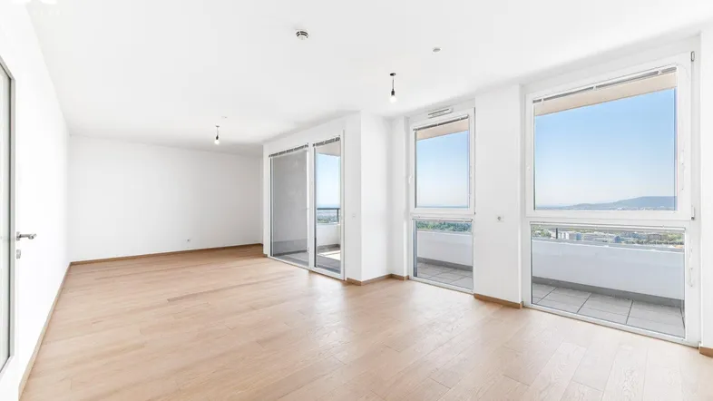 Helles Wohnzimmer mit Holzboden, großen Fenstern und Zugang zum Balkon mit Stadtblick.