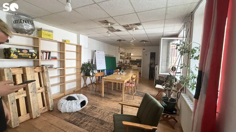Geräumiger Büroraum mit Holzboden, Regalen und einem großen Holztisch, ideal für Besprechungen.