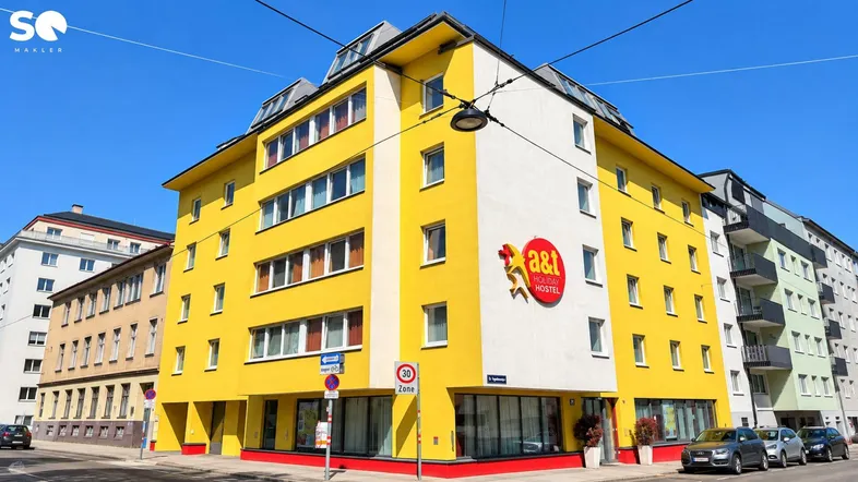 Auffälliges gelbes Gebäude mit roten Akzenten und vielen Fenstern, das ein Hostel beherbergt.