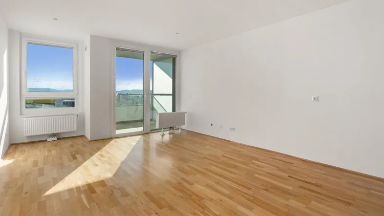 Helles Wohnzimmer mit Parkettboden und Zugang zu einem Balkon mit Weitblick.