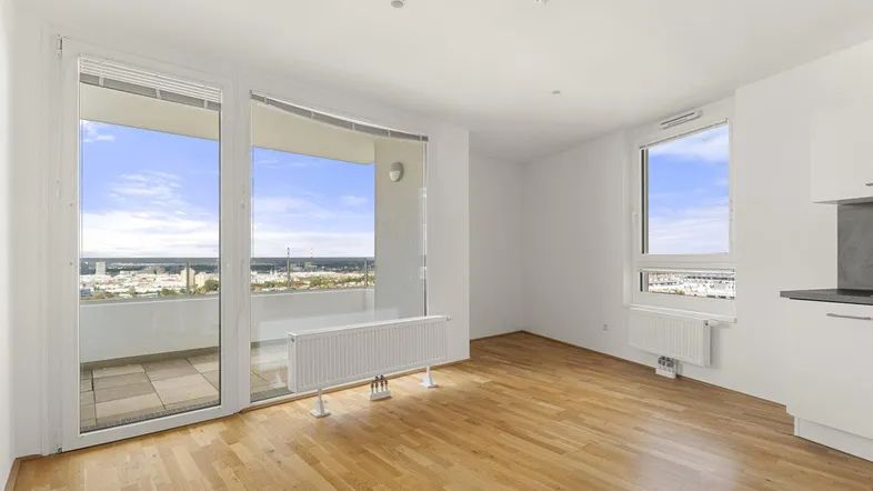 Helles Wohnzimmer mit Parkettboden, großen Fenstern und Zugang zu einem Balkon mit Stadtblick.