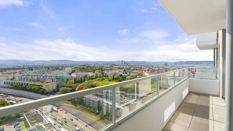 Geräumiger Balkon mit Glasbrüstung und weitem Blick über die Stadt und die umliegende Landschaft.