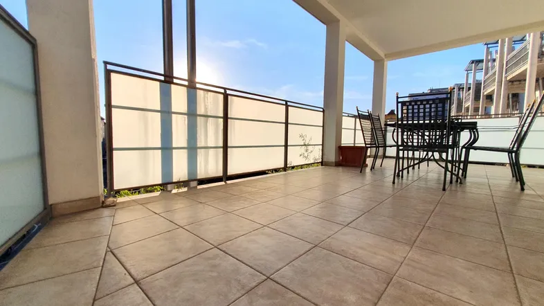Geräumige Terrasse mit Fliesenboden und Metallmöbeln, ideal für entspannte Stunden im Freien.