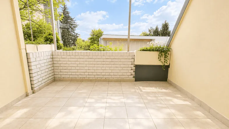 Überdachter Balkon mit Fliesenboden und Blick ins Grüne, ideal für entspannte Stunden.