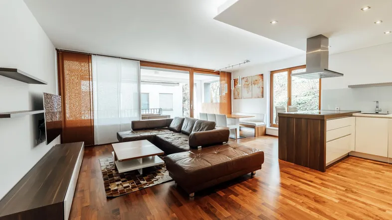 Geräumiger offener Wohn- und Essbereich mit moderner Küche, Holzboden und Zugang zur Terrasse.