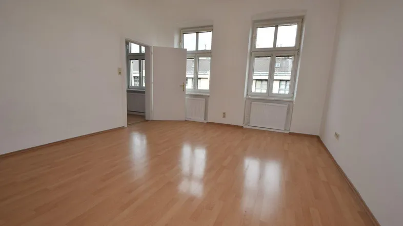 Heller Raum mit Laminatboden und zwei Fenstern, der vielseitig nutzbar ist.